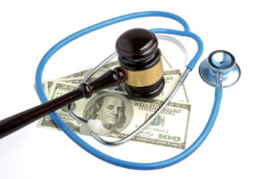 Still life composition of a judge's gavel, stethoscope, and US 100 dollar bills